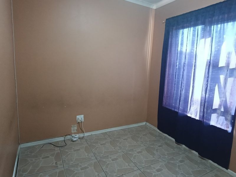 An empty bedroom featuring tiled flooring and neutral wall paint, offering a blank canvas for potential interior design updates.