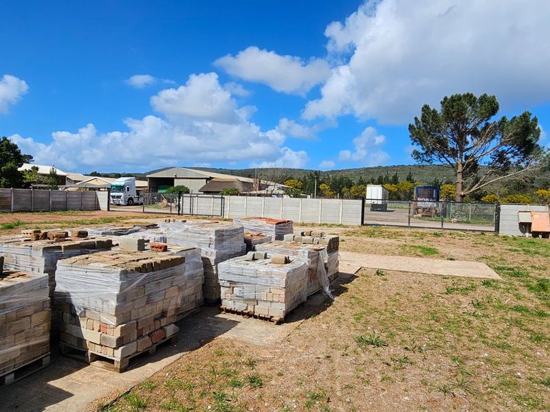 An expansive industrial yard area featuring a secure precast concrete boundary wall, metal gate access, and a level concrete hardstanding surface.