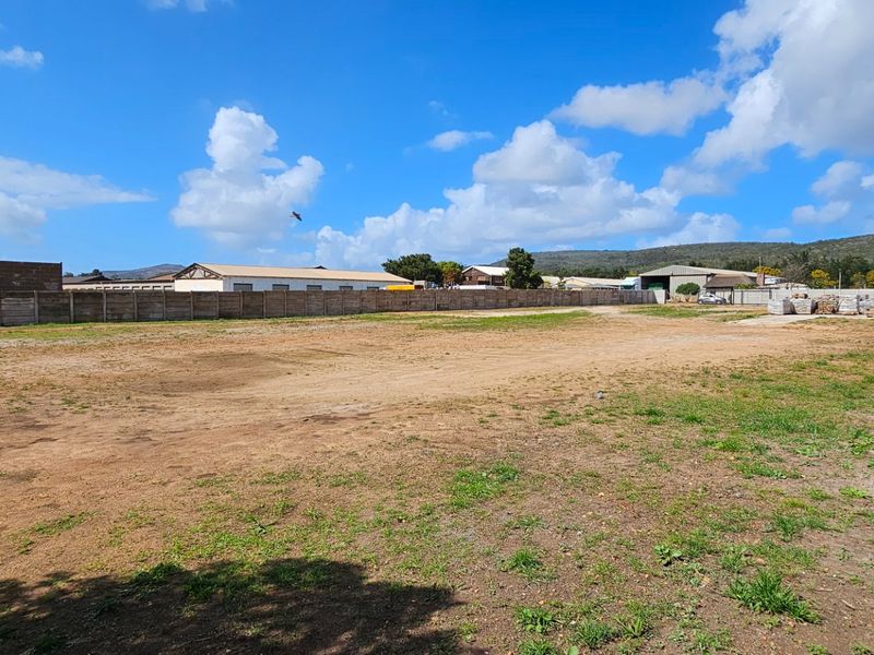 A large, open industrial plot featuring a precast concrete boundary wall with security razor wire fencing.