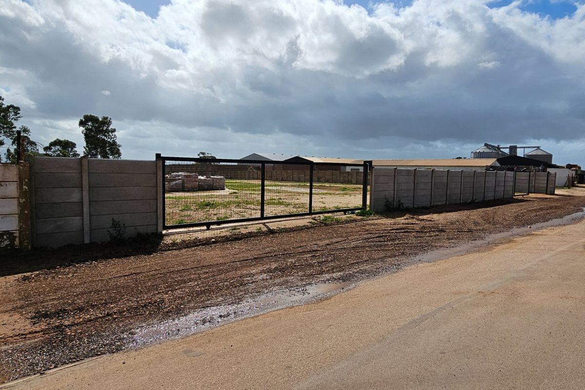Industrial property frontage featuring a precast concrete boundary wall and metal sliding gate access point.