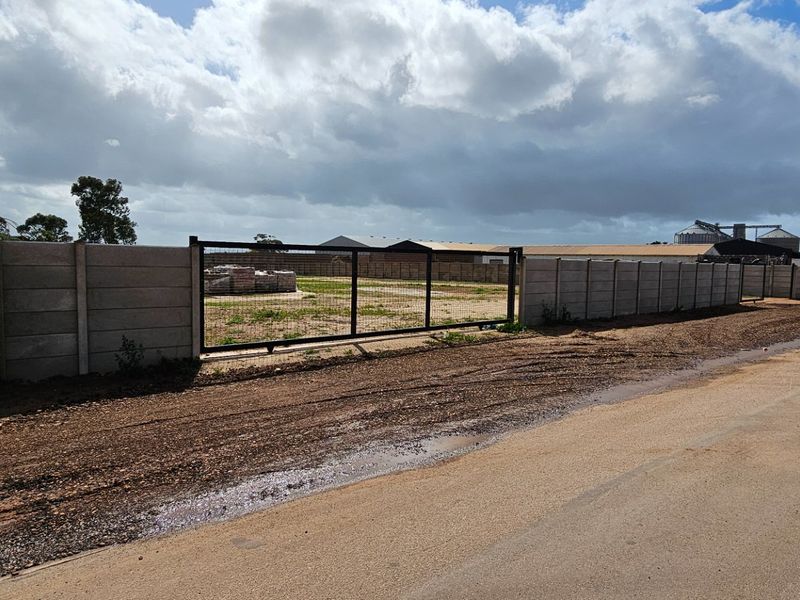 Industrial property frontage featuring a precast concrete boundary wall and metal sliding gate access point.