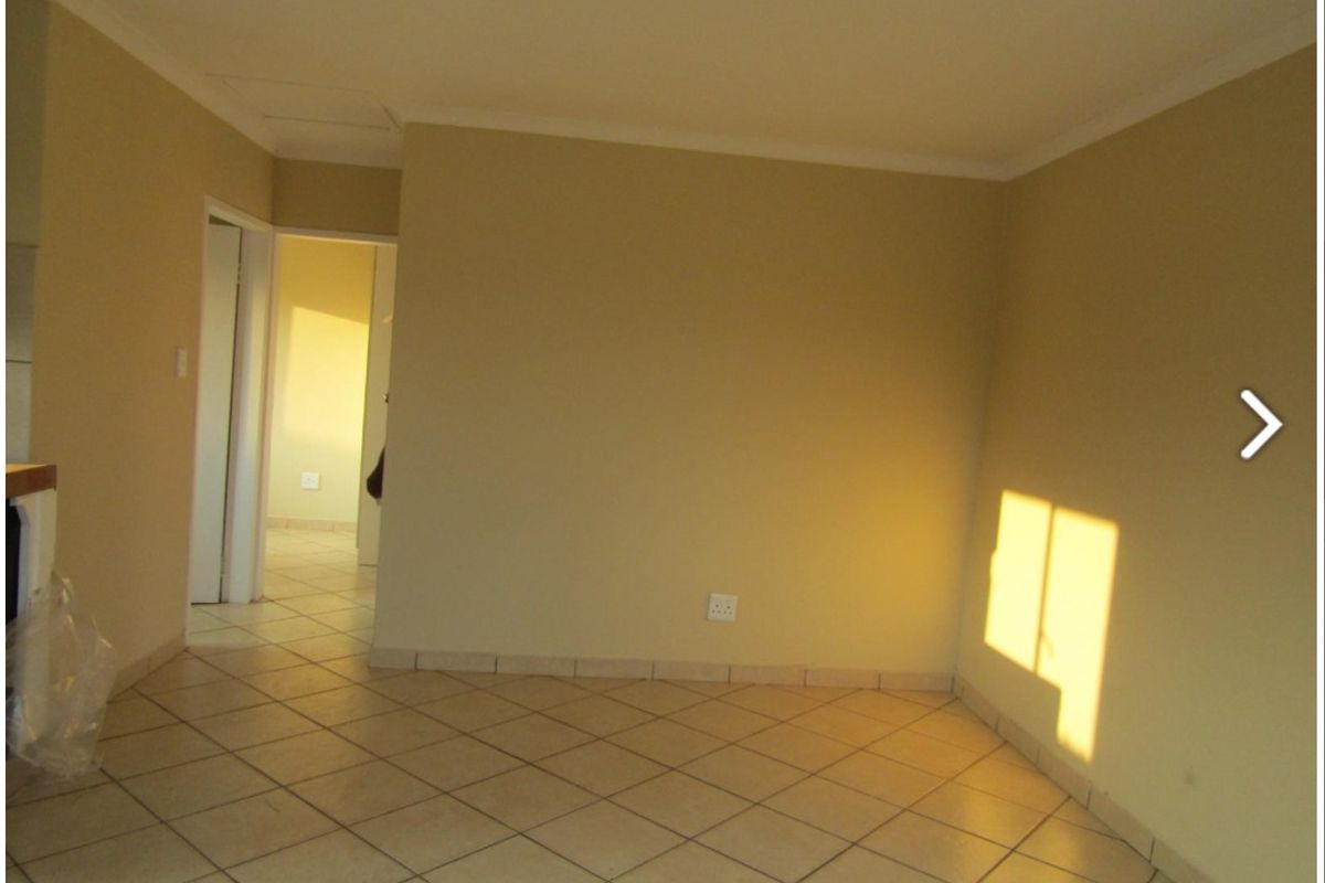 An empty living area featuring neutral wall paint and tiled flooring, providing a blank canvas for interior design.