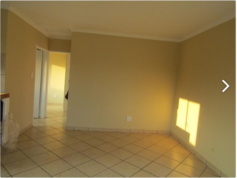 An empty living area featuring neutral wall paint and tiled flooring, providing a blank canvas for interior design.