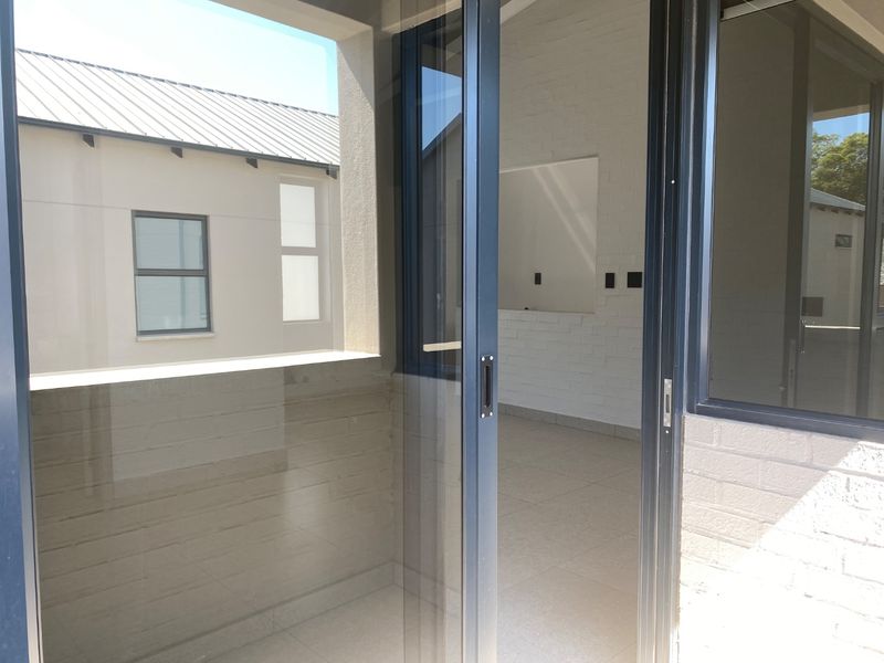 A clean, modern covered patio area featuring tiled flooring and large sliding glass doors, providing a seamless transition to the interior living space.