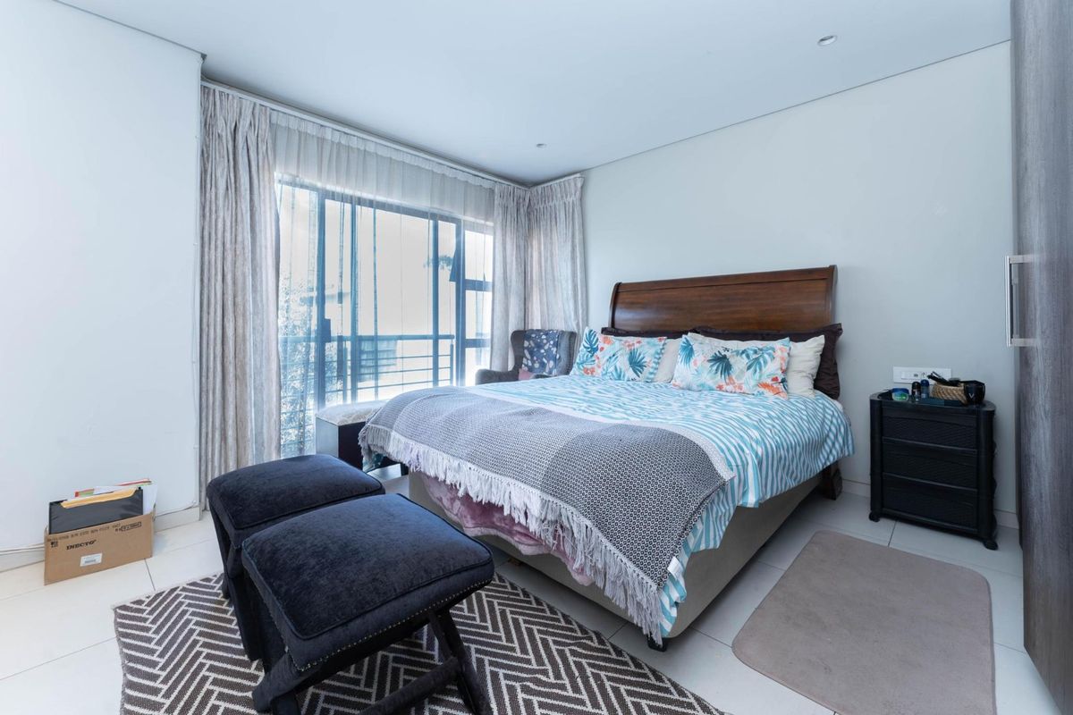A well-maintained bedroom featuring tiled flooring, recessed lighting, and a large sliding glass door providing natural light and access to an outdoor area.