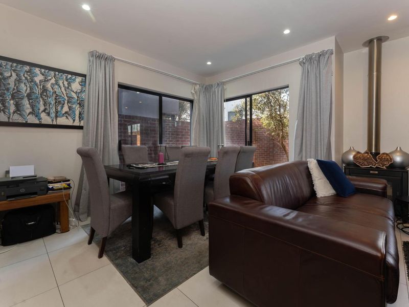 Open-plan living and dining area featuring tiled floors, recessed lighting, and a modern freestanding fireplace with direct access to the rear garden.