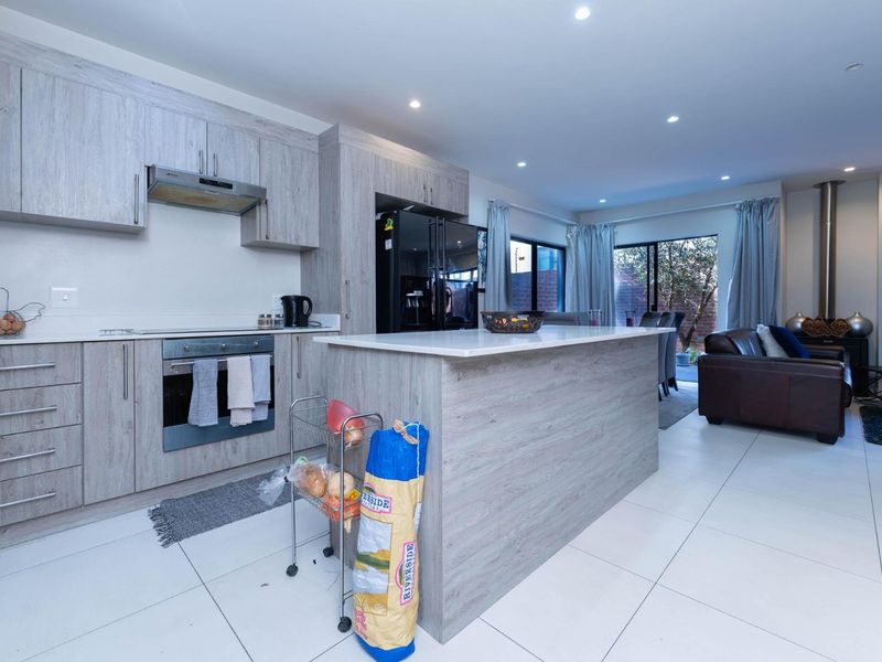 Modern open-plan living area featuring a contemporary kitchen with a central island, built-in appliances, and a cozy fireplace, seamlessly flowing into the lounge space.