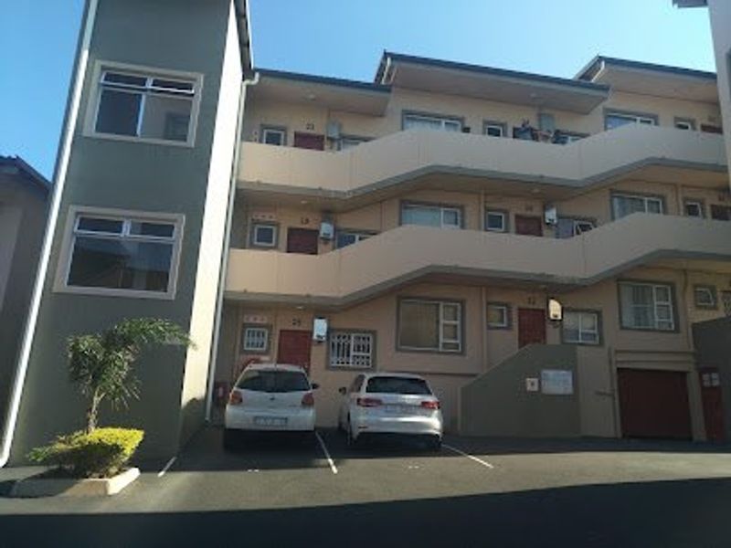 Exterior view of a multi-story apartment complex featuring external staircases, balconies, and dedicated parking spaces.