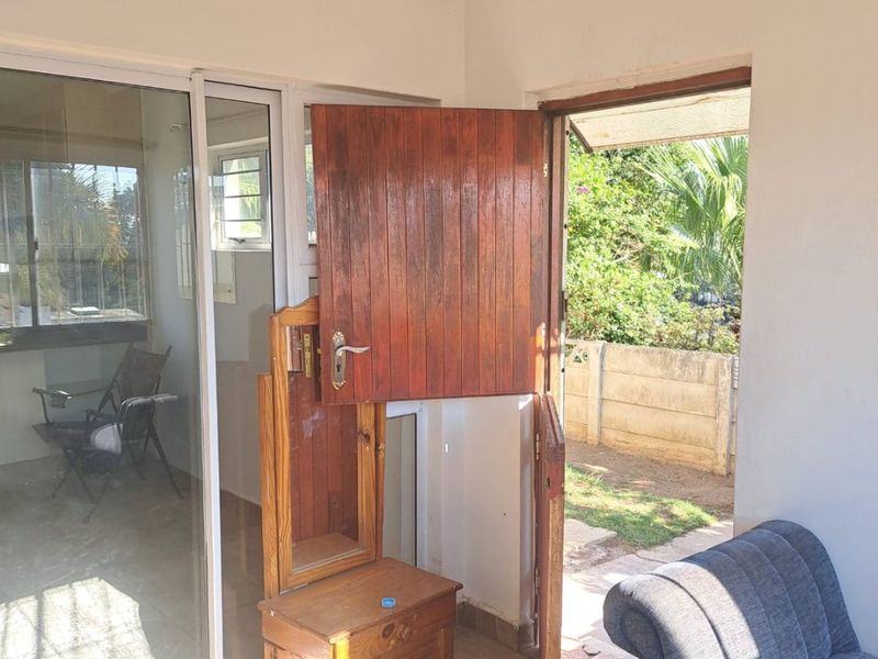 A covered patio area featuring tiled flooring, a sliding glass door, and a unique stable-style wooden door leading to the garden.