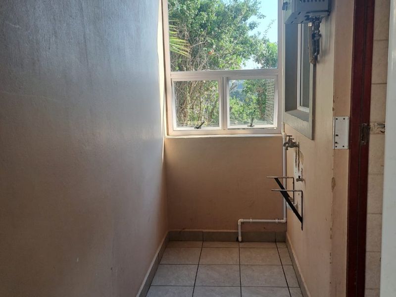 A functional laundry area featuring tiled flooring, plumbing connections for appliances, and a wall-mounted gas water heater.