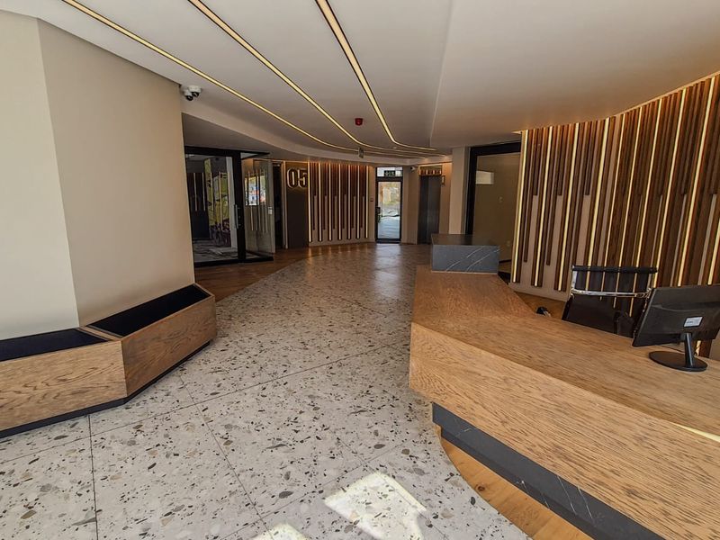 Modern commercial lobby featuring high-end terrazzo flooring, custom timber slat wall paneling, and a sleek built-in reception desk with integrated lighting.