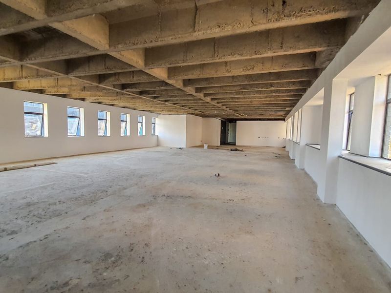 Expansive open-plan commercial space featuring an exposed concrete waffle ceiling, large windows providing natural light, and unfinished concrete flooring ready for fit-out.
