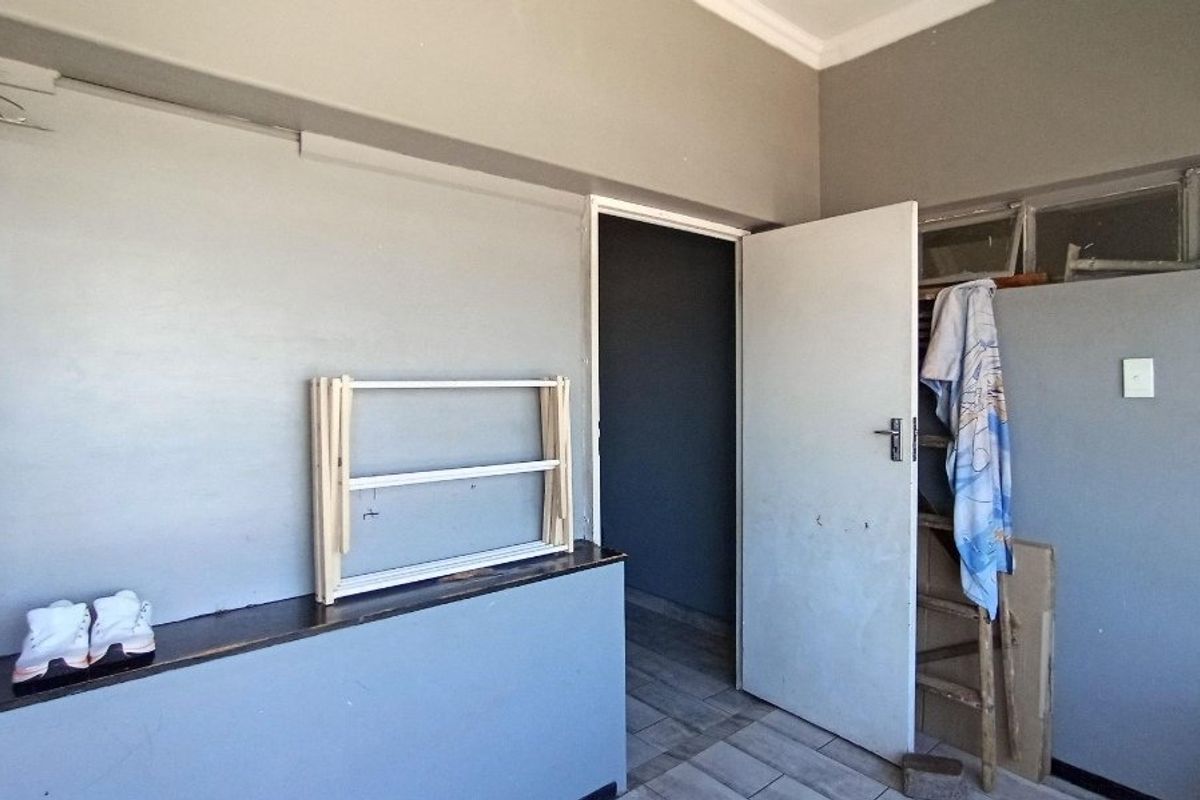 A vacant bedroom featuring tiled flooring, a built-in ledge, and coved ceilings, requiring cosmetic updates to improve its overall condition.