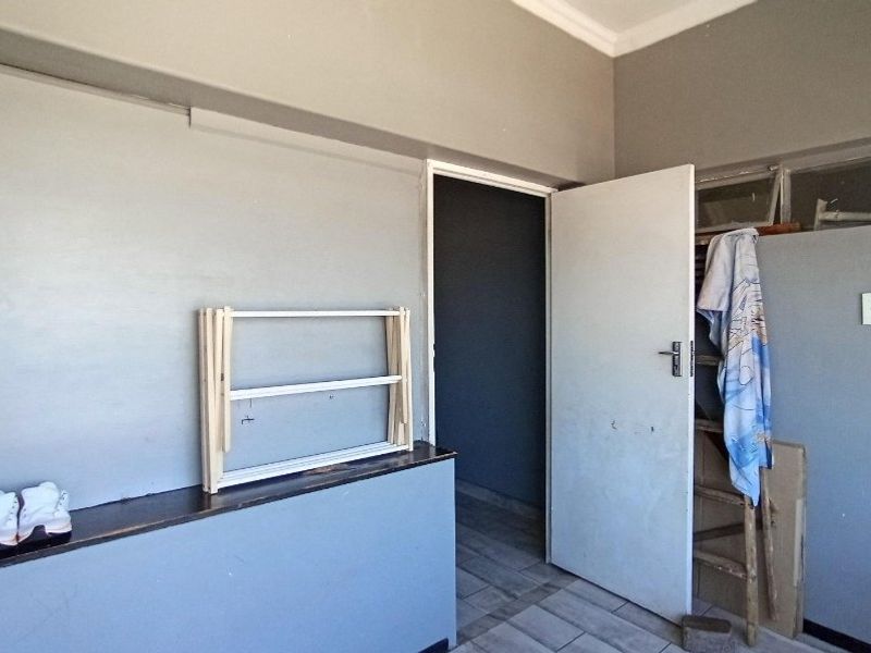 A vacant bedroom featuring tiled flooring, a built-in ledge, and coved ceilings, requiring cosmetic updates to improve its overall condition.