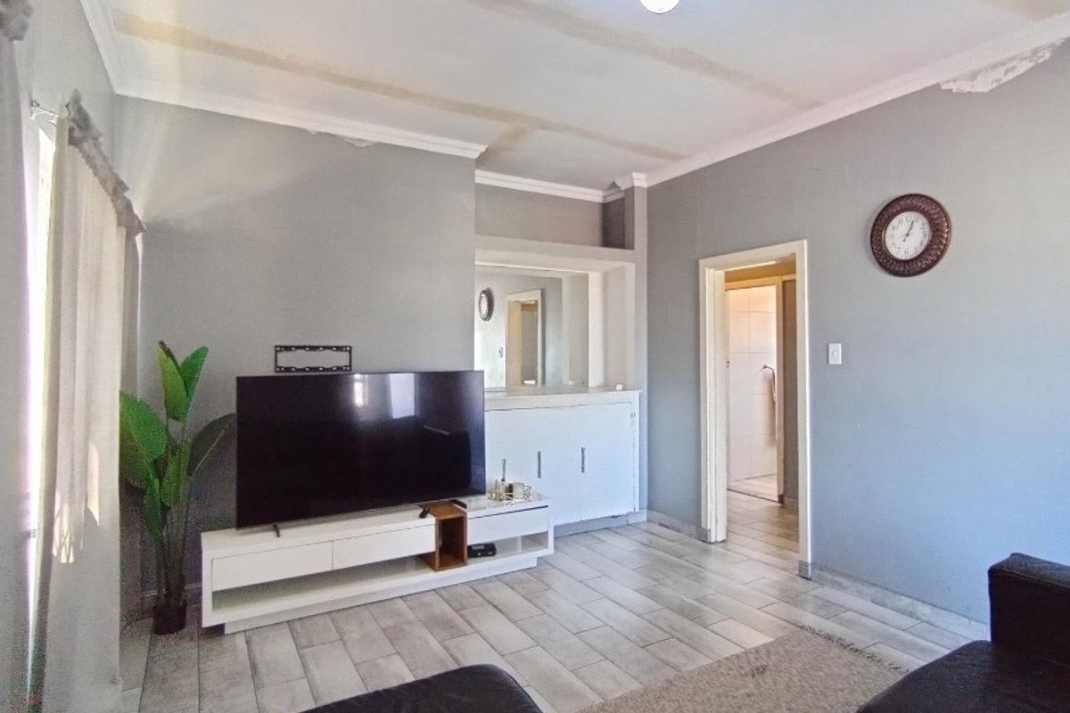 A living room featuring tiled flooring, coved ceilings, and built-in cabinetry, providing a functional space with potential for cosmetic updates.