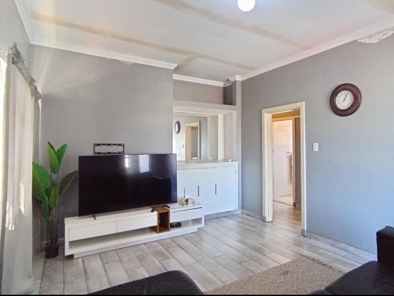 A living room featuring tiled flooring, coved ceilings, and built-in cabinetry, providing a functional space with potential for cosmetic updates.