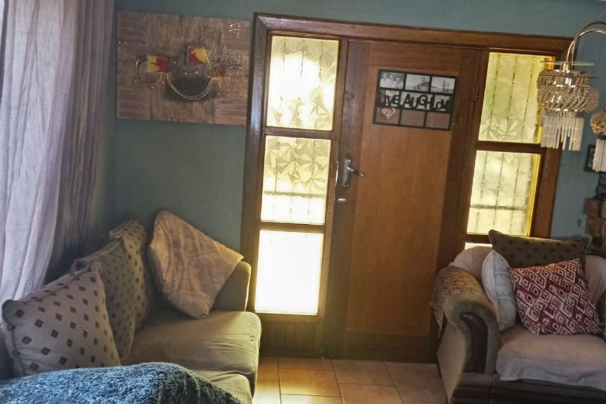 A living room featuring a warm timber tongue and groove ceiling, tiled flooring, and a classic timber-framed glass entrance door.