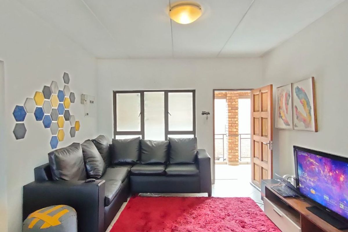 A living room area featuring tiled flooring, a ceiling light fixture, and access to an outdoor space through a doorway.