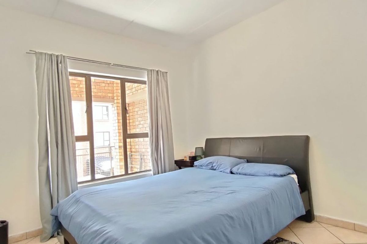 A bedroom featuring tiled flooring, neutral walls, and an aluminium-framed window providing natural light.