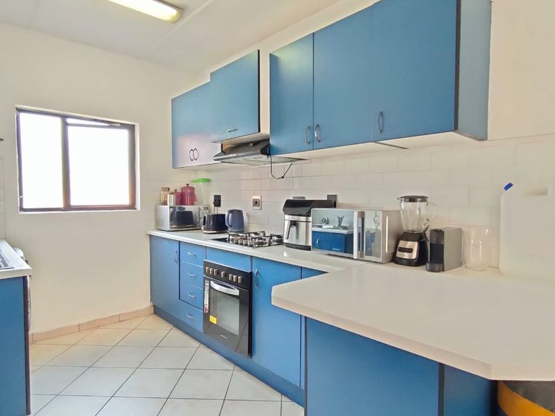 A functional kitchen featuring blue cabinetry, white countertops, a built-in oven with gas hob, and a tiled backsplash.