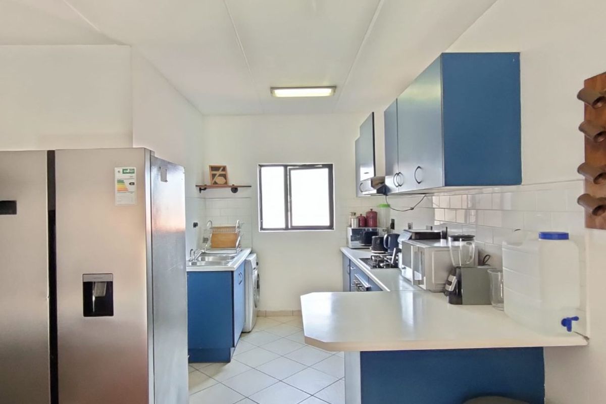 A functional kitchen featuring blue cabinetry, white subway tile backsplash, tiled flooring, and a breakfast bar counter.