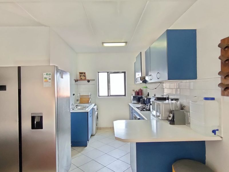 A functional kitchen featuring blue cabinetry, white subway tile backsplash, tiled flooring, and a breakfast bar counter.