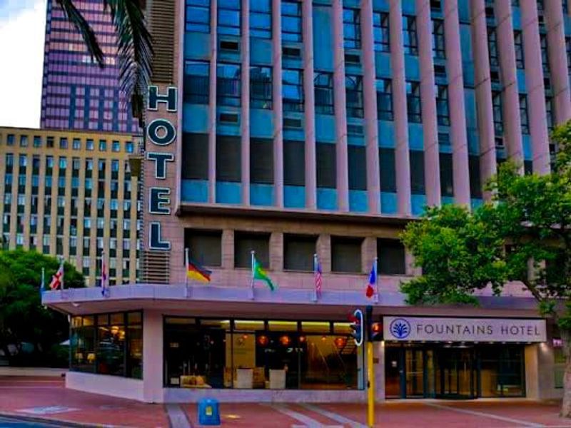 Street-level view of the Fountains Hotel entrance, featuring a modern glass facade, prominent signage, and a professional commercial exterior design.