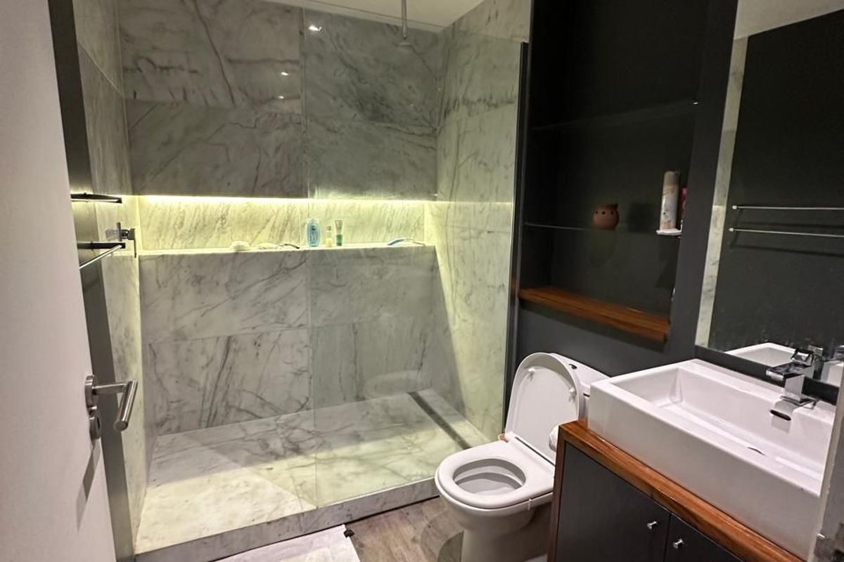 Modern bathroom featuring a spacious walk-in shower with marble-look tiling, integrated LED lighting, a sleek vanity unit, and contemporary fixtures.