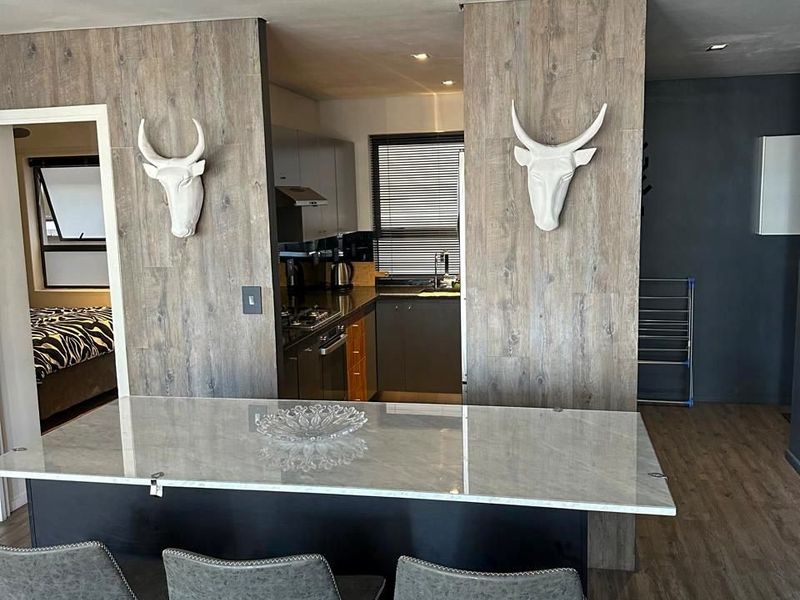 Open plan living area featuring a modern kitchen island with stone countertop, integrated cabinetry, and wood-look feature wall panels.