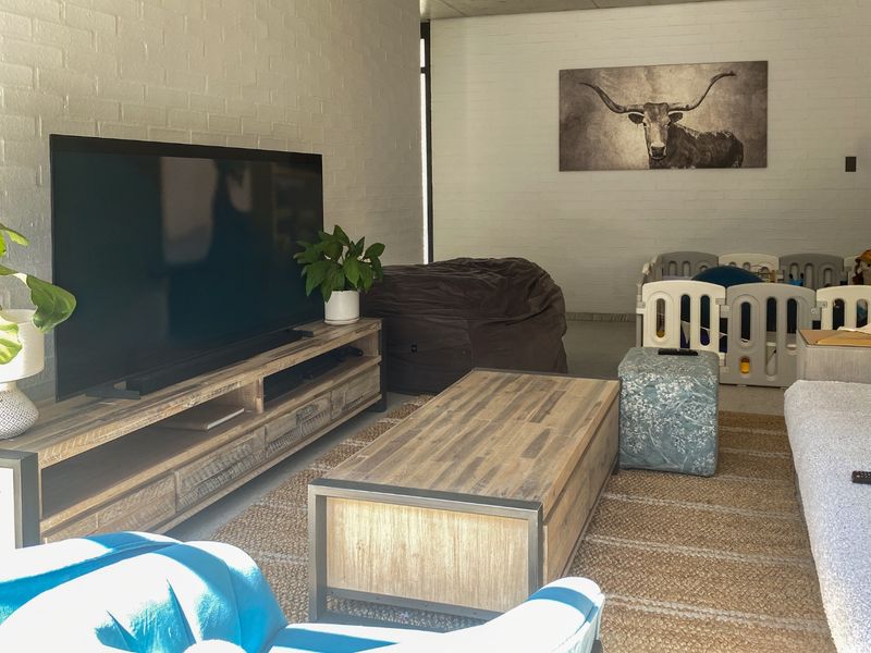A living room featuring painted brick walls and neutral flooring, providing a versatile space for relaxation and family activities.
