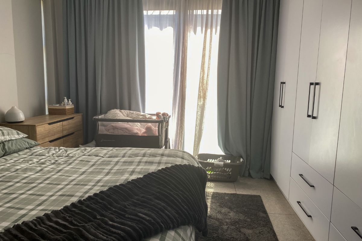 A well-maintained bedroom featuring built-in cupboards, tiled flooring, and a sliding glass door providing natural light.