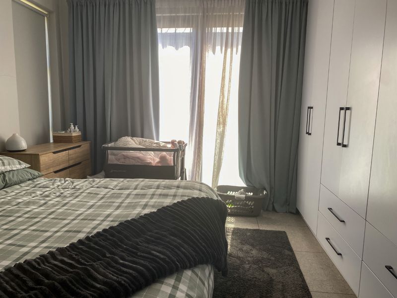 A well-maintained bedroom featuring built-in cupboards, tiled flooring, and a sliding glass door providing natural light.