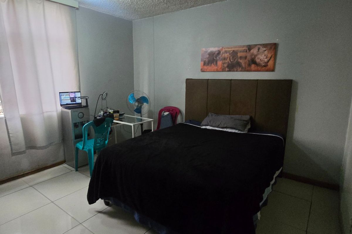 A functional bedroom featuring tiled flooring and a built-in cupboard, offering a neutral space ready for personalization.