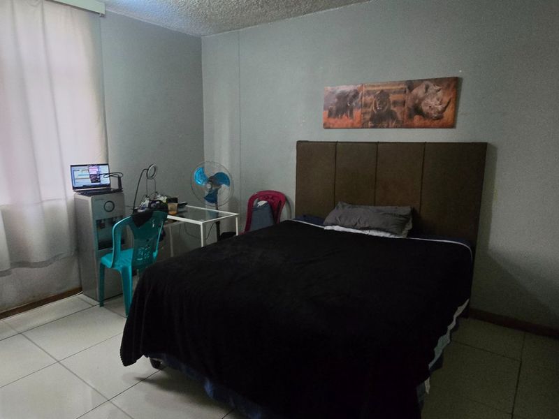 A functional bedroom featuring tiled flooring and a built-in cupboard, offering a neutral space ready for personalization.