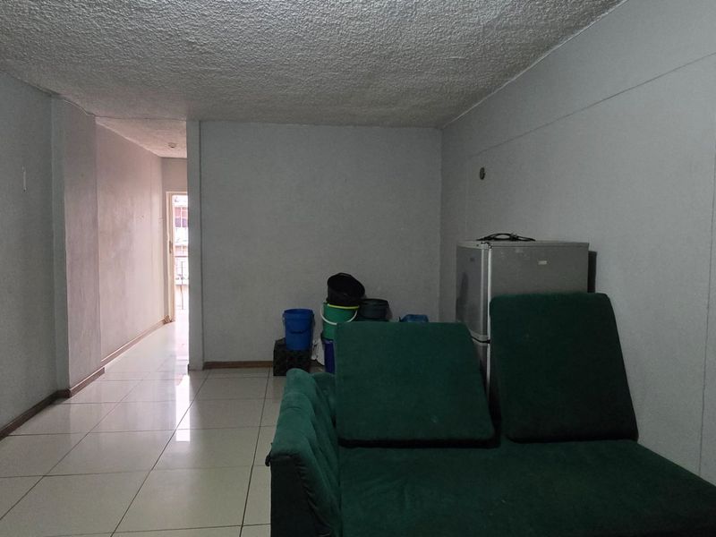 A living area featuring tiled flooring and a textured ceiling, offering a blank canvas for potential renovation and interior design updates.