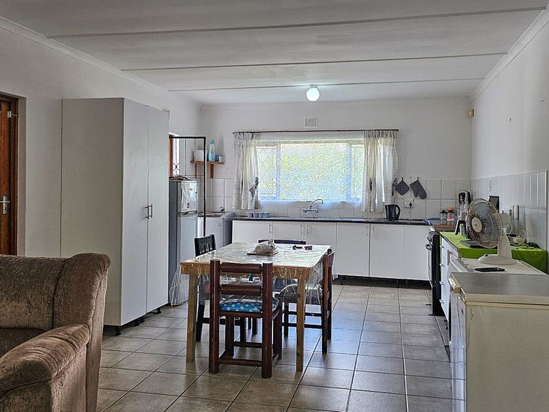 Open-plan kitchen and dining area featuring tiled flooring, functional cabinetry, and a tiled backsplash, offering a practical layout for daily living.