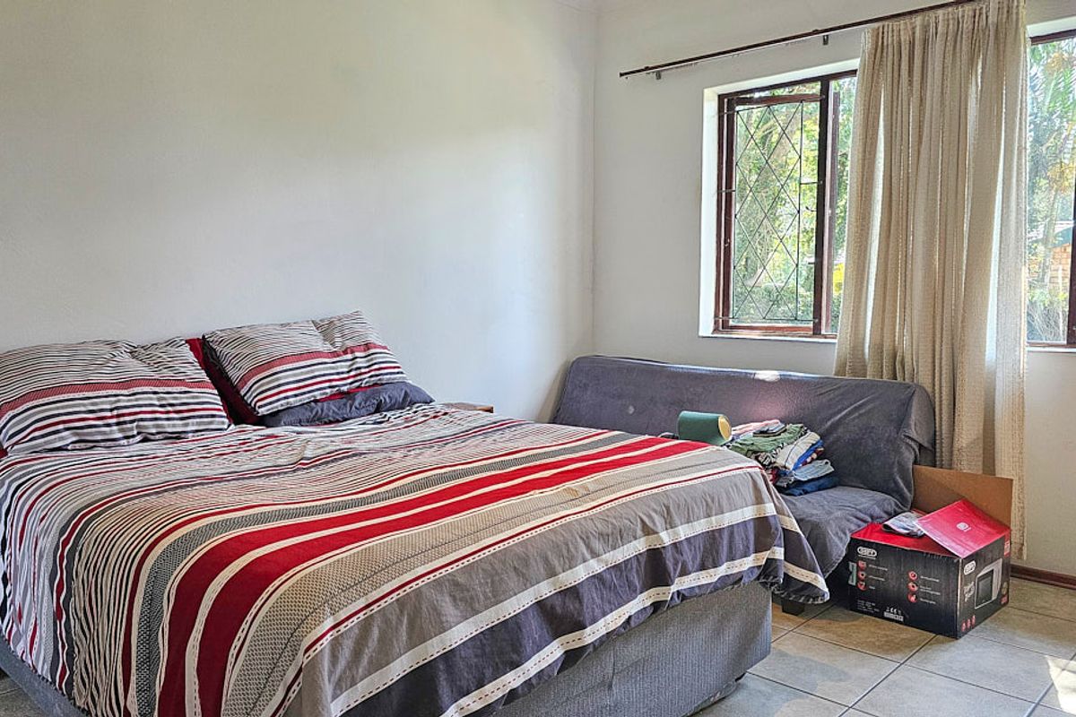 A functional bedroom featuring tiled flooring and windows fitted with security bars, providing a neutral space ready for personalization.