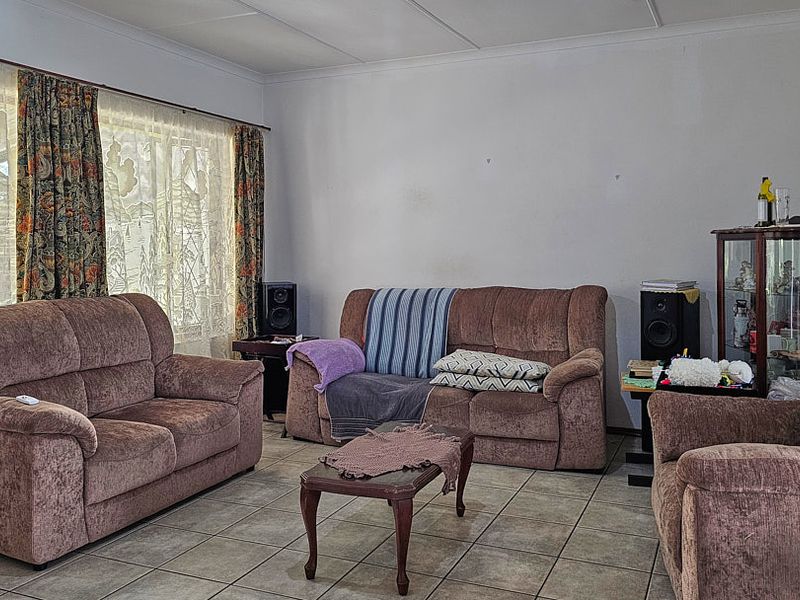 A living room featuring tiled flooring and a coved ceiling, providing a neutral base for potential interior updates.