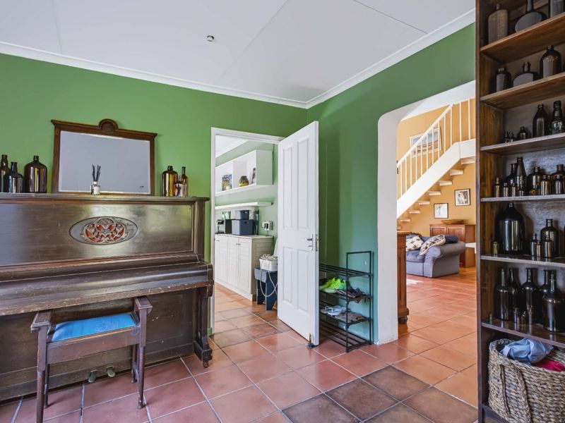 An entrance area featuring terracotta-style tiled flooring, green painted walls, and an open archway leading to a staircase and adjacent living space.