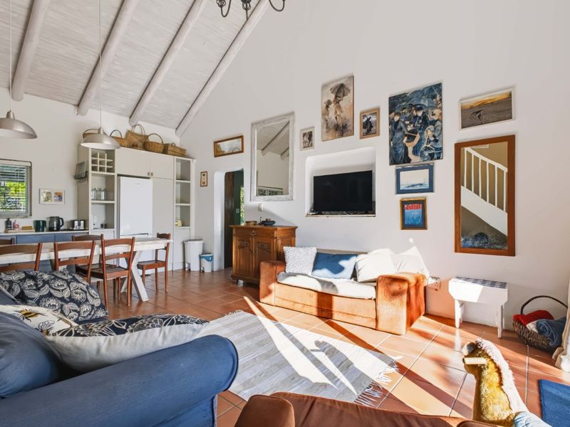 Spacious open-plan living and kitchen area featuring high vaulted ceilings with exposed rafters and classic terracotta floor tiles.