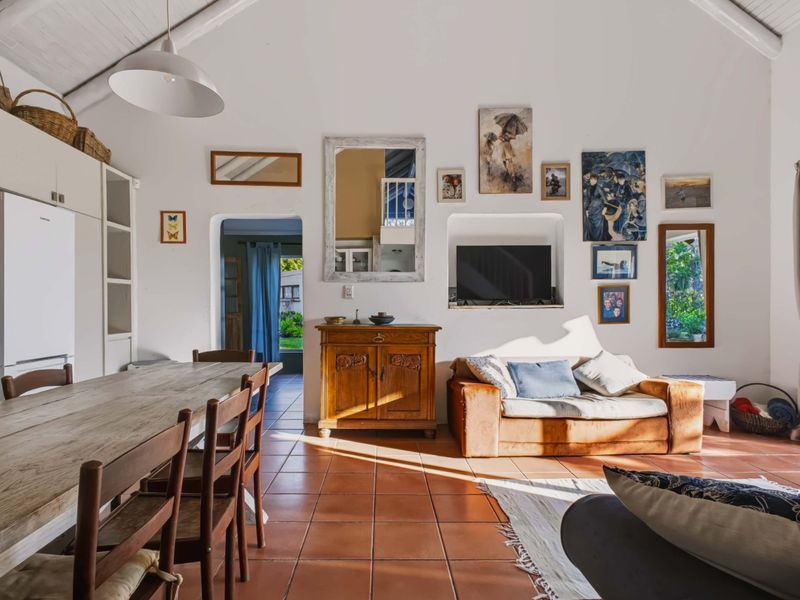 Spacious open-plan living and dining area featuring vaulted ceilings with exposed beams and classic terracotta floor tiles, creating a warm and inviting atmosphere.