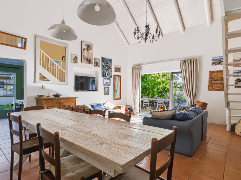 Spacious open-plan living and dining area featuring high vaulted ceilings with exposed rafters, terracotta flooring, and direct access to the outdoor patio.