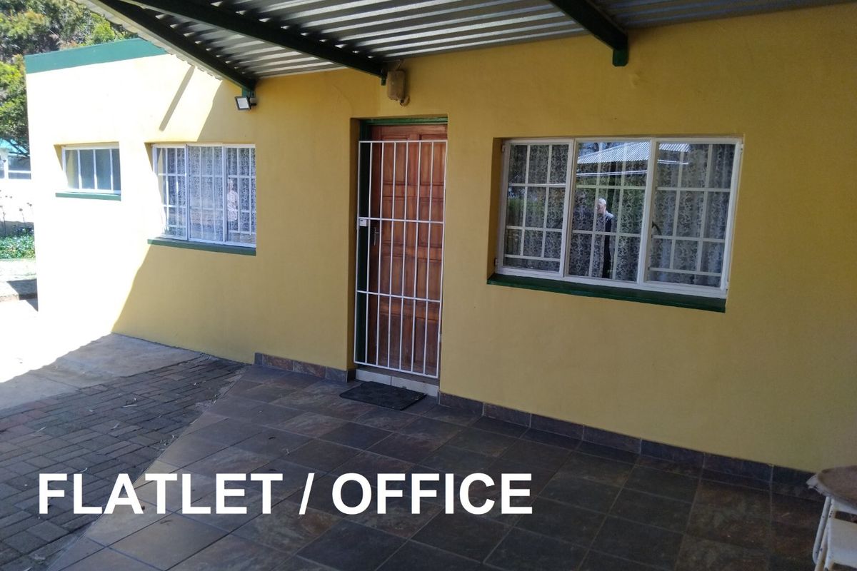 A covered patio area leading to a flatlet or office entrance, featuring tiled flooring, security gates, and a corrugated metal roof structure.