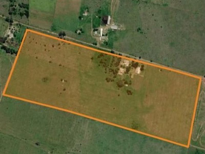 An aerial view of a large, open farm plot with a clearly defined boundary, featuring expansive grazing land and scattered vegetation.