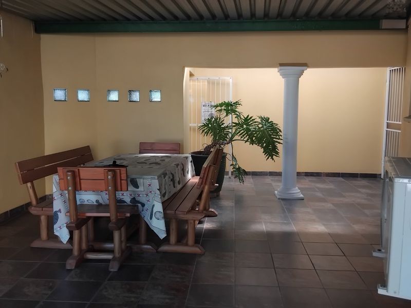 A covered outdoor patio area featuring tiled flooring, a decorative column, and glass block wall accents, providing a functional space for outdoor dining.