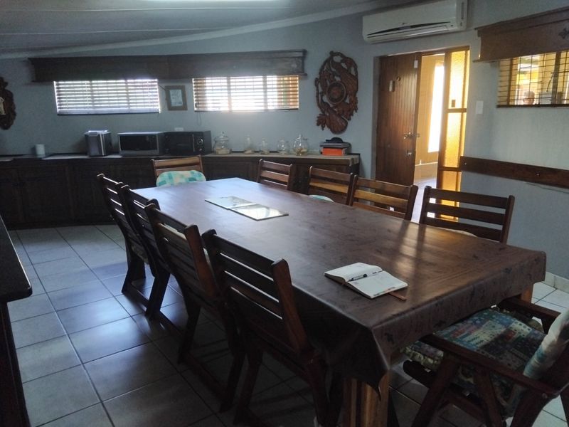 A spacious dining area featuring tiled flooring, built-in cabinetry, and a wall-mounted air conditioning unit, providing a functional space for family meals.