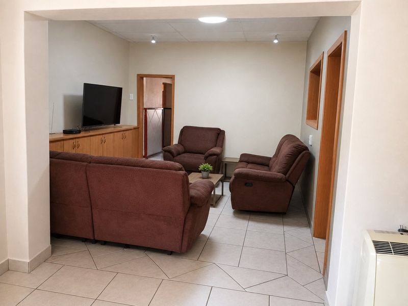 A functional living room featuring tiled flooring, built-in cabinetry, and recessed ceiling lighting, providing a comfortable and practical space.