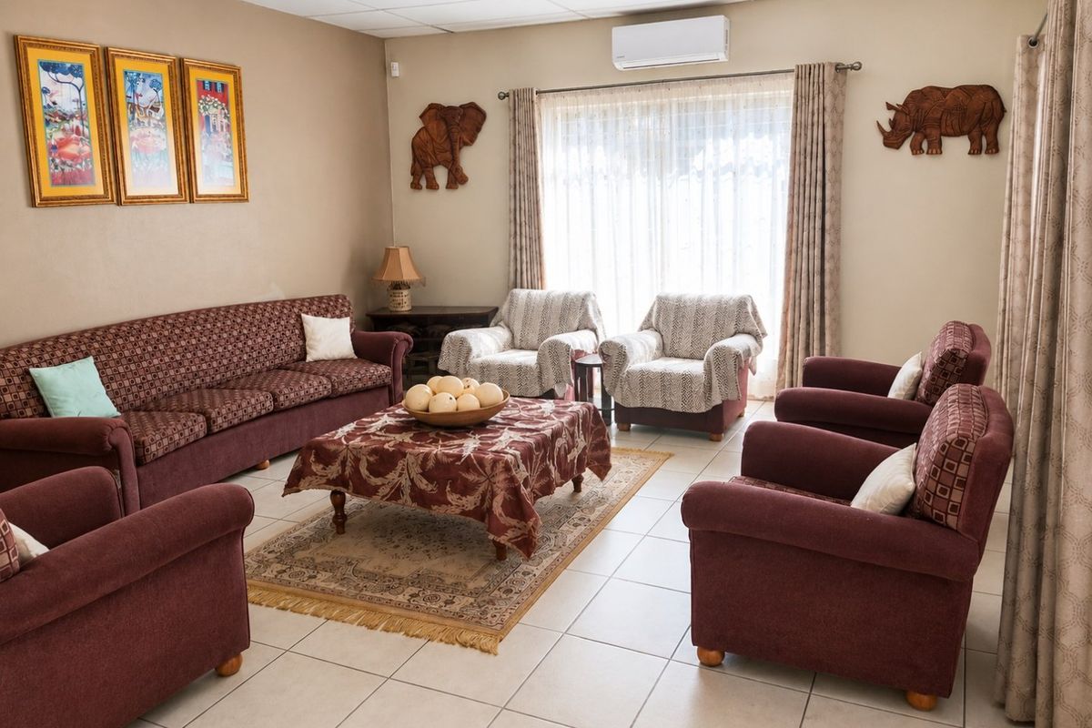 A spacious living room featuring tiled flooring, a drop ceiling, and a wall-mounted air conditioning unit, providing a comfortable and functional living space.