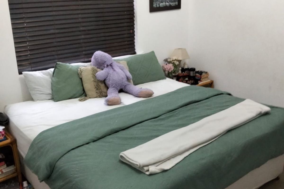 A functional bedroom featuring a wall-mounted air conditioning unit and dark venetian blinds, providing a neutral base for potential interior updates.