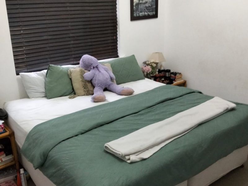 A functional bedroom featuring a wall-mounted air conditioning unit and dark venetian blinds, providing a neutral base for potential interior updates.